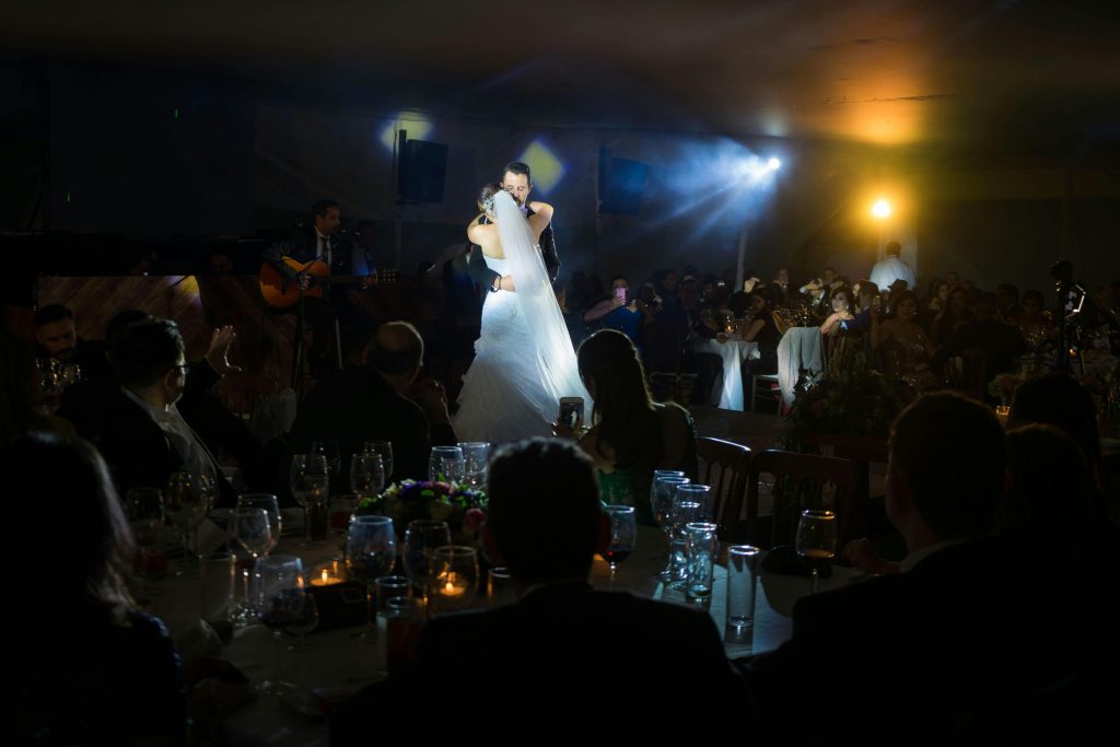 A bride and groom share a romantic dance at a glowing wedding reception.